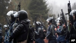 Riot police officers hold their weapons as they attempt to stop demonstrators protesting in Almaty on January 5, 2022. 