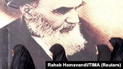 Iranian women walk past a poster of the late Supreme Leader Ayatollah Ruhollah Khomeini, who died in 1989. (file photo)