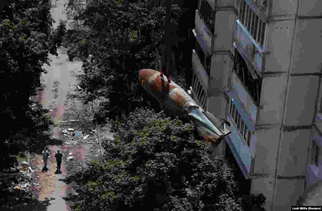 People watch as a defused 500-kilogram Russian bomb that did not detonate when it landed on an apartment building in March is lowered from the roof by members of a specialized team in Kharkiv, Ukraine, on June 23.