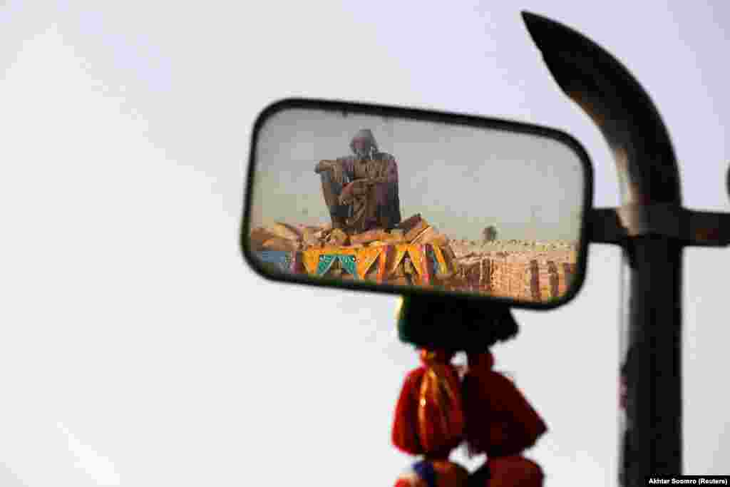Chaneser, 45, is reflected in a mirror of a tractor as he takes a break from work at a brick kiln factory in Jacobabad, Pakistan.