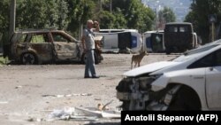 A man walks past a barricade made with destroyed police cars in the besieged Ukrainian city of Lysychansk. 