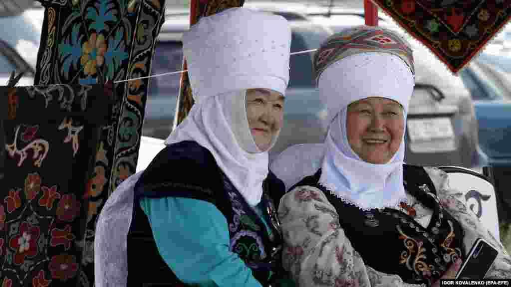 Kyrgyz women in festive traditional attire smile as they watch the events unfold.&nbsp;