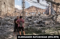 Local residents look at destroyed buildings in Lysychansk after heavy fighting on June 18.