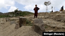 An Afghan boy stands in a graveyard in the village of Gayan after the burial of relatives who died in the earthquake.