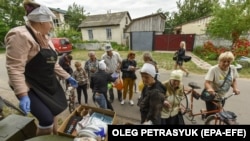 Люди получают продукты в качестве гуманитарной помощи в селе Новоселовка Черниговской области, Украина, 23 июня 2022 года