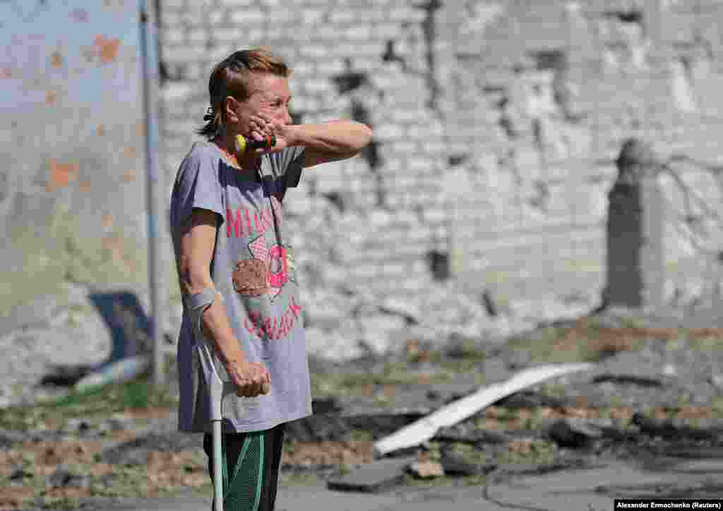 A woman breaks down in front of her destroyed apartment building.