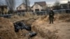 A Ukrainian soldier stands next to a mass grave with bodies of civilians, who according to residents were killed by Russian soldiers in Bucha, Kyiv region, on April 6.