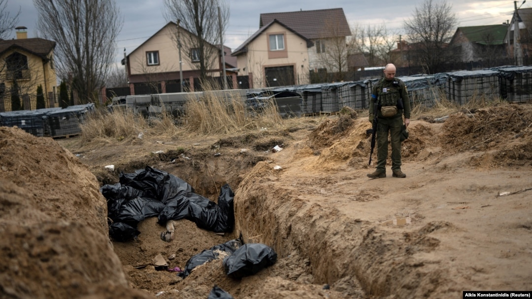 A Ukrainian soldier stands next to a mass grave with bodies of civilians, who according to residents were killed by Russian soldiers in Bucha, Kyiv region, on April 6.