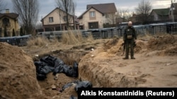 A Ukrainian soldier stands next to a mass grave with bodies of civilians, who according to residents were killed by Russian soldiers in Bucha, Kyiv region, on April 6.