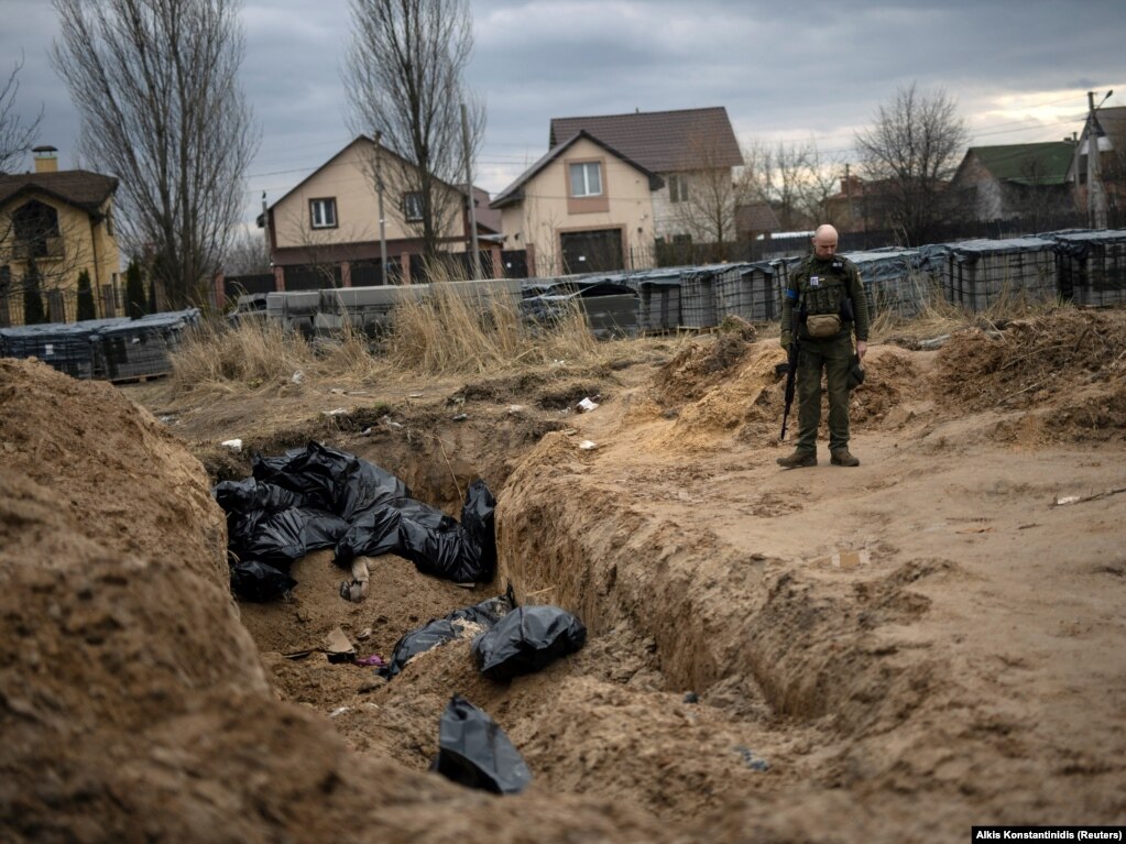 An April 6 photo shows a Ukrainian soldier next to a mass grave of civilians killed during the Russian occupation of Bucha.