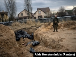 An April 6 photo shows a Ukrainian soldier next to a mass grave of civilians killed during the Russian occupation of Bucha.