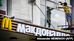 Un muncitor înlătură marca iconică a restaurantelor McDonald's, Moscova, 17 iunie 2022.
