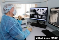 Egy fogorvos nézi egy páciens röntgenfelvételét a domogyedovói városi fogászati klinikán. Korábban, a Covid–19-zárlat idején a fogászati klinikák csak a fogászati vészhelyzeteket látták el. A kép 2020. június 15-én készült