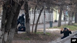 Вооруженный омоновец задерживает двух человек во время «антитеррористической операции» в дни январских событий в Алматы