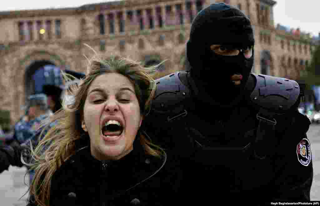 Një zyrtar policor arreston një protestuese në Jerevan, ku qytetarët po kërkojnë që kryeministri armen, Nikol Pashinian të japë dorëheqje për shkak të marrëveshjes së arritur me Azerbajxhanin. (AP/Hayk Baghdasaryan)