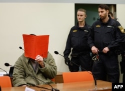 Фархад Н. закриває обличчя, коли його фотографують у суді, Мюнхен, Німеччина, 16 січня 2026 року
