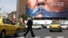 A woman in Tehran walks past an anti-American billboard depicting US President Donald Trump and the Strait of Hormuz. 