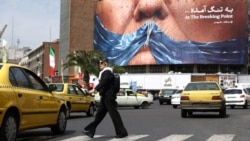 A woman in Tehran walks past an anti-American billboard depicting US President Donald Trump and the Strait of Hormuz. 