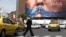 A woman in Tehran walks past an anti-American billboard depicting US President Donald Trump and the Strait of Hormuz. 