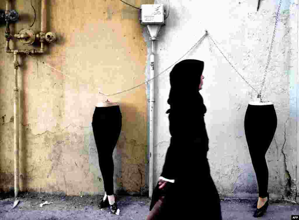 An Iranian woman walks past mannequins locked to a gas pipe in northern Tehran. (AFP/Behrouz Mehri)