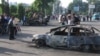Uzbekistan -- Residents walk pass a car burnt during the unrest in the eastern Uzbek town of Andijon, May 13, 2005