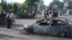 Uzbekistan -- Residents walk pass a car burnt during the unrest in the eastern Uzbek town of Andijon, May 13, 2005