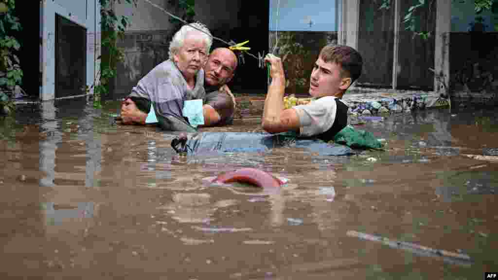 Residents assist an elderly woman as floodwaters rise in Slobozia Conachi, Romania, on September 14. The floods, which have claimed at least 10 lives from Poland to Romania, have submerged towns and homes, triggering large-scale evacuations.