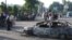 Residents walk past a burnt-out car following the unrest in the eastern Uzbek town of Andijon on May 13, 2005.