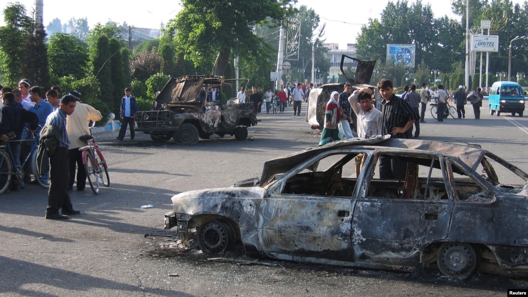 Residents pass burnt-out cars after the unrest in the eastern Uzbek town of Andijon on May 13, 2005.