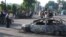 Residents pass burnt-out cars after the unrest in the eastern Uzbek town of Andijon on May 13, 2005.
