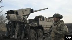 A Ukrainian serviceman stands next to a Caesar 8x8 wheeled self-propelled howitzer on a frontline in an undisclosed location, Southern Ukraine on February 14, 2024,