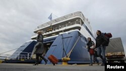 Passengers make their way past a ferry at Piraeus port near Athens on February 10. Ferry service is one victim of the union strikes.