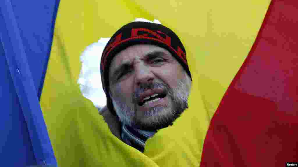 Un protestatar, scandând lozinci prin drapelul României