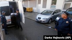 Montenegrin police officers escort a one of several people suspected of planning a coup in Podgorica late last year. (file photo)