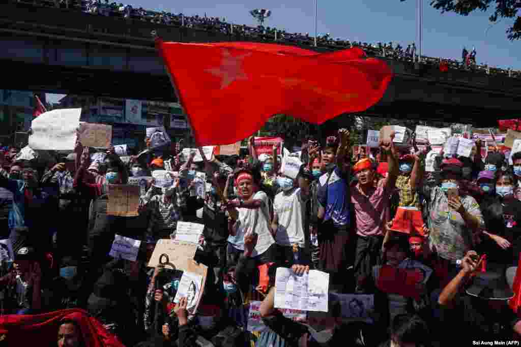 معترضان هنگام شرکت در تظاهرات علیه کودتای نظامی اول فبروری در شهر یانگون بیرق حزب لیگ ملی برای دموکراسی (NLD) را به اهتزاز درآورده اند (عکس از Sai Aung Main / AFP) &nbsp;