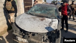 Një burrë e shikon një veturë të dëmtuar në një zonë të goditur nga sulmet ajrore amerikane në qytetin irakian, Al-Qaim, 3 shkurt 2024.