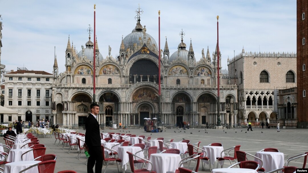 Un ospătar stand printer mesele goale la un restaurant din Piața San Marco din Veneția, Italia