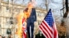 Iranian hardliners burn a cutout poster depicting British ambassador to Iran Robert Macaire along with British and U.S. flags during a memorial for passengers of Ukraine airplane, at the Tehran University in Tehran, January 14, 2020