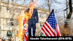 Iranian hardliners burn a cutout poster depicting British ambassador to Iran Robert Macaire along with British and U.S. flags during a memorial for passengers of Ukraine airplane, at the Tehran University in Tehran, January 14, 2020