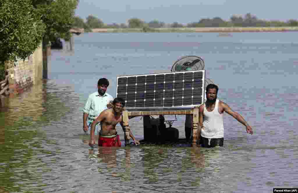 Victimele inundațiilor fără precedent provocate de ploile musonice folosesc un pat pentru a-și salva bunurile din casa lor inundată, în Jaffarabad, Pakistan, la 5 septembrie 2022. Foto: AP Photo/Fareed Khan