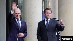 Presidenti francez, Emmanuel Macron dhe kancelari gjerman, Olaf Scholz përshëndesin me dorë gazetarët përpara një takimi në Pallatin Elysee në Paris. Fotografi nga arkivi. 