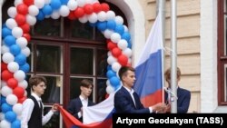 Школьники поднимают флаг РФ на торжественной линейке, посвященной Дню знаний
