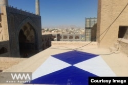 A blue shield on a rooftop in Iran.