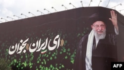This picture shows a billboard bearing the portrait of Iranian supreme leader Ayatollah Ali Khamenei and a quote reads in Persian 'Sing Oh Iran' at the Enqelab Square in Tehran on July 9.