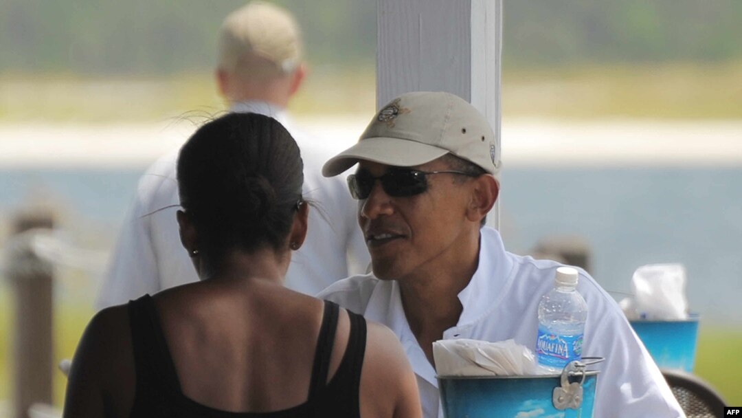 U.S. President Barack Obama chats with his wife, Michelle, during lunch at Lime's Bayside Bar and Grill in Panama City, Florida, on August 14.