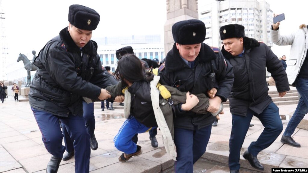 Полицейские задерживают и ведут к автозаку активиста на площади Республики в Алматы. 20 ноября 2022 года
