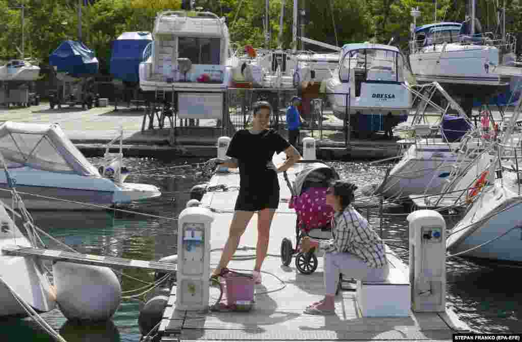 Ukrainians enjoy the summer weather at the Black Sea Yacht Club. Due to the military conflict and the danger of mines, yachts cannot leave port.