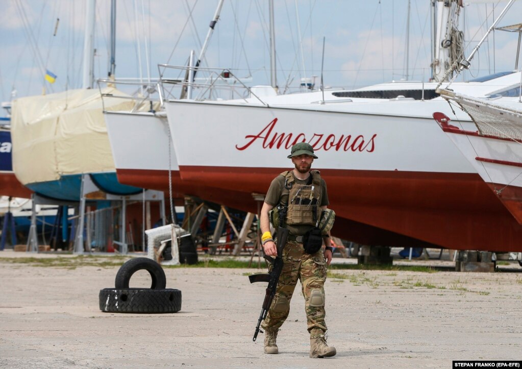 Një luftëtar i armatosur i Mbrojtjes Territoriale të Ukrainës duke ecur pranë Klubit të Jahteve të Detit të Zi.
