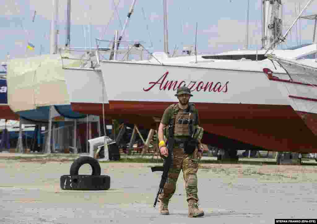 An armed Ukrainian Territorial Defense fighter walks the pier at the Black Sea Yacht Club.