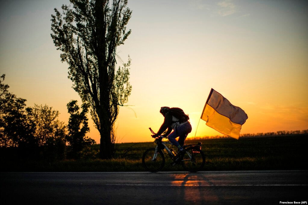 Një burrë duke ngarë biçikletën me një flamur ukrainas në rrugën midis Odesës dhe Mykolajivit.